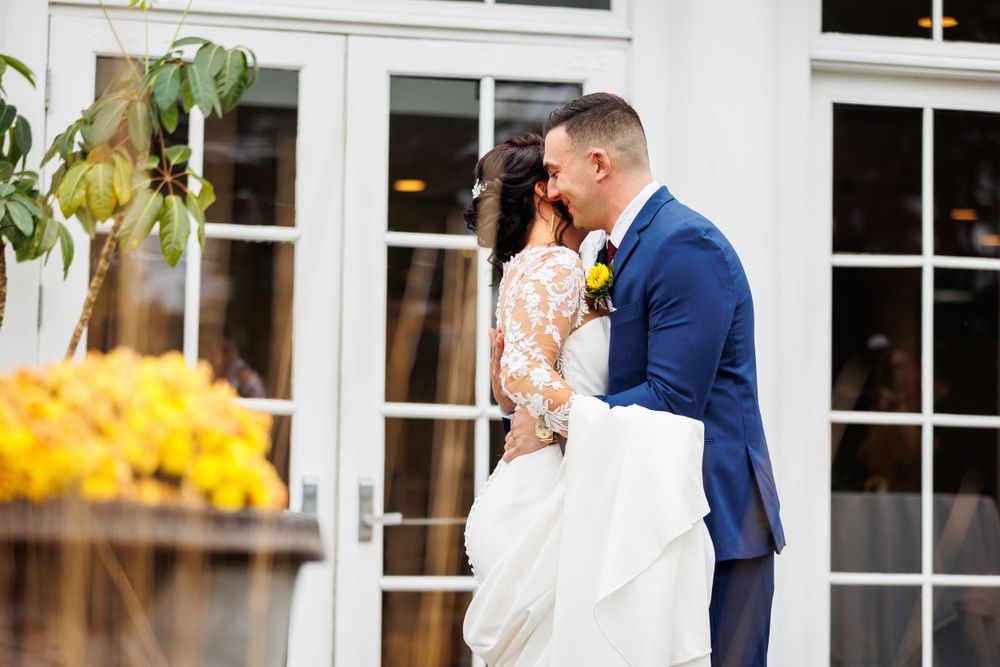 Bride and groom sharing a kiss outside elegant white French doors on wedding day.