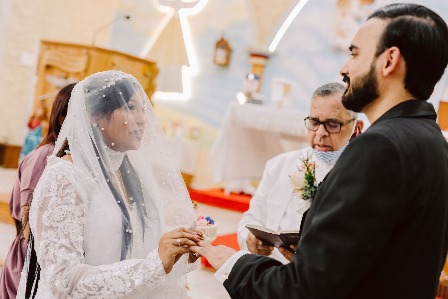 A wedding ceremony in progress with the couple exchanging rings in front of an officiant.
