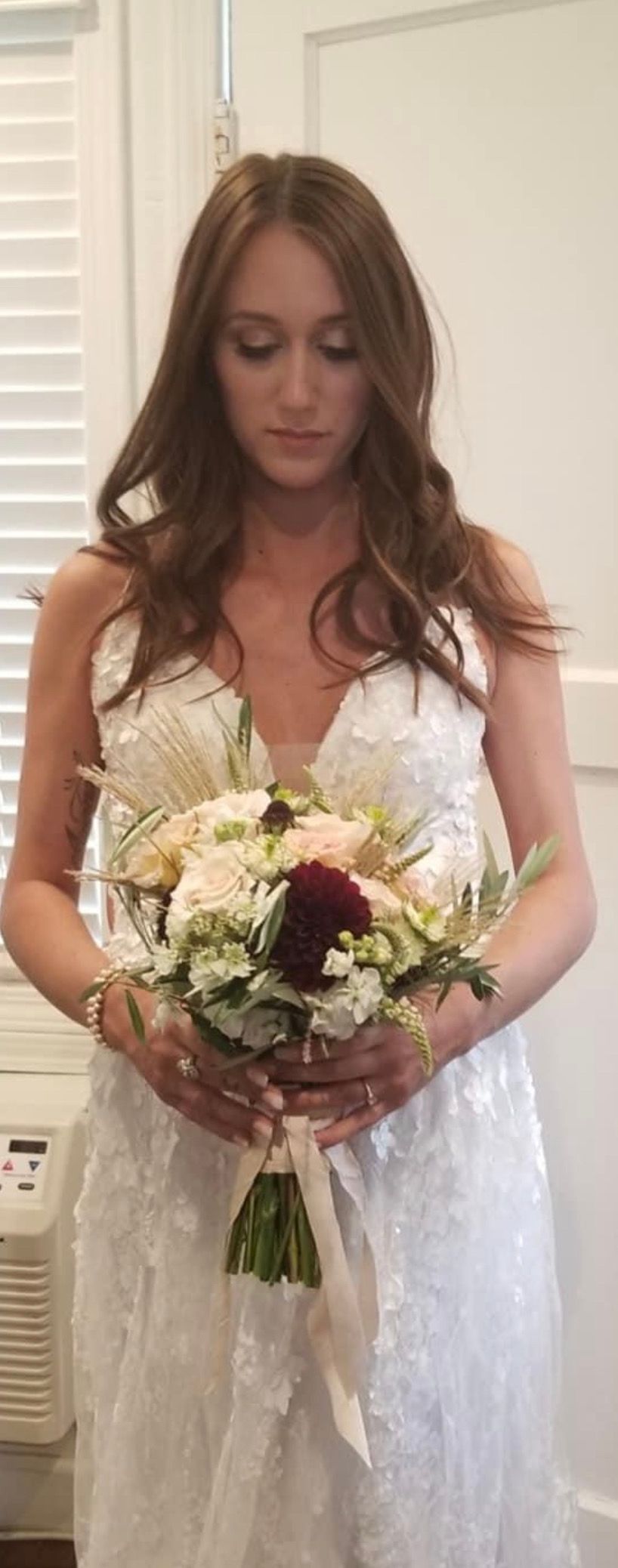 A beautiful bride holding a bouquet of flowers in her room at the Casablanca Inn. Santa Cruz CA
