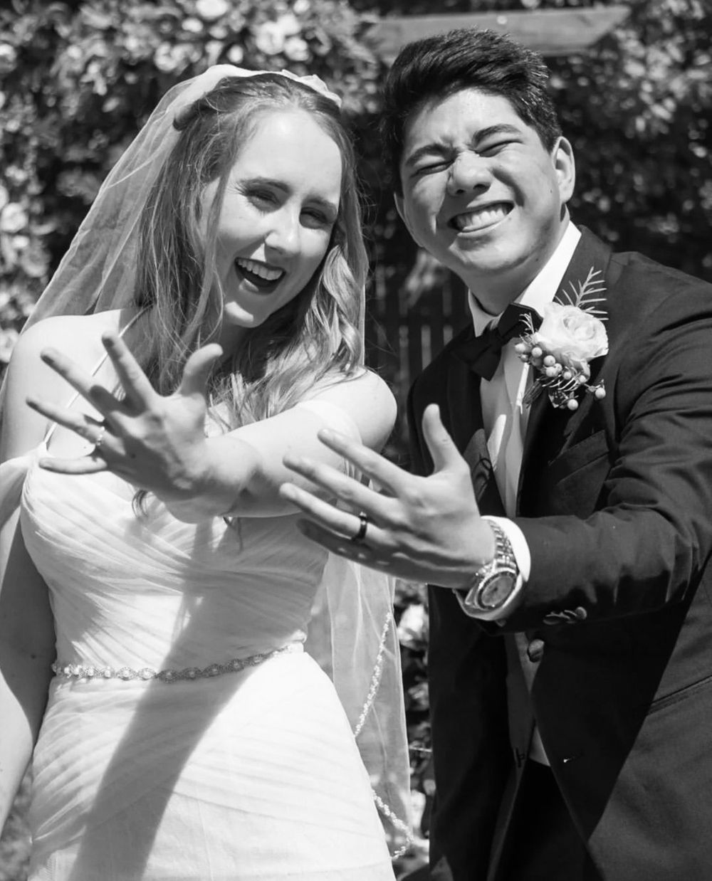 A beautiful couple in their wedding attire, striking a pose for a timeless black and white photograph.