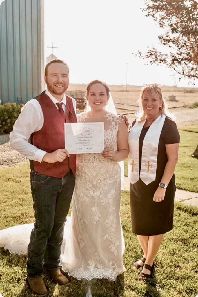 A bride and groom, along with their officiant, pose for a picture at a ranch wedding.