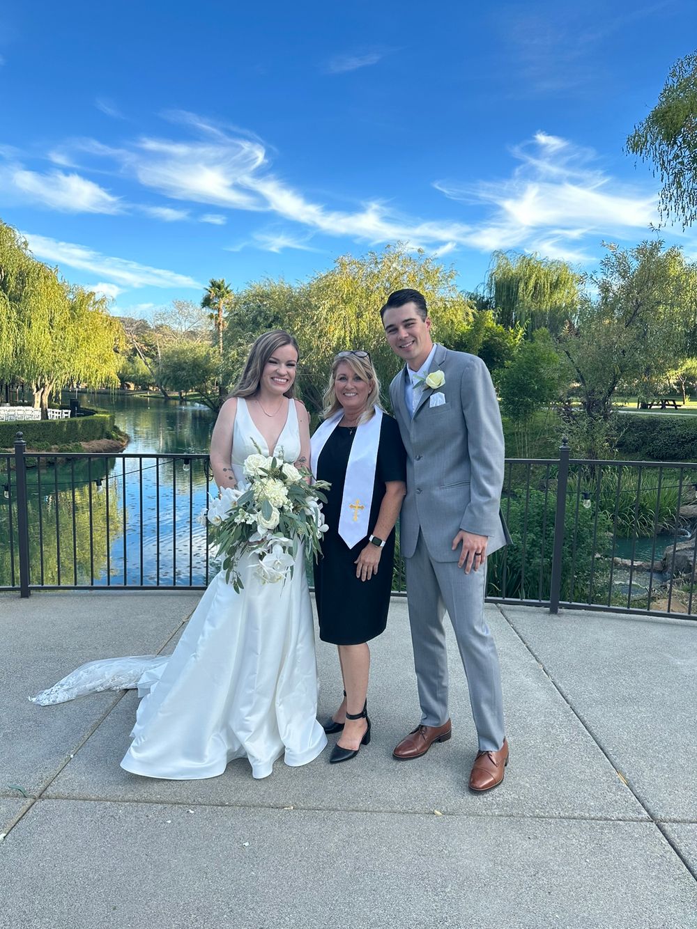 A beautiful couple and their parents stand proudly in front of a serene pond on their special day. Love and family unite