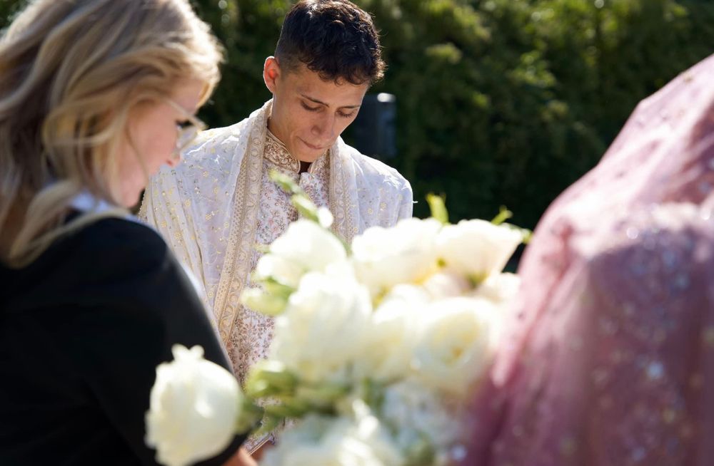 A Christian groom in a white robe and a Hindu bride in a veil during a Sacramento wedding ceremony