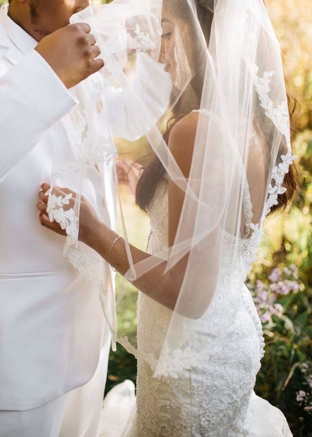 black groom lifts the veil of his black bride wearing her wedding dress