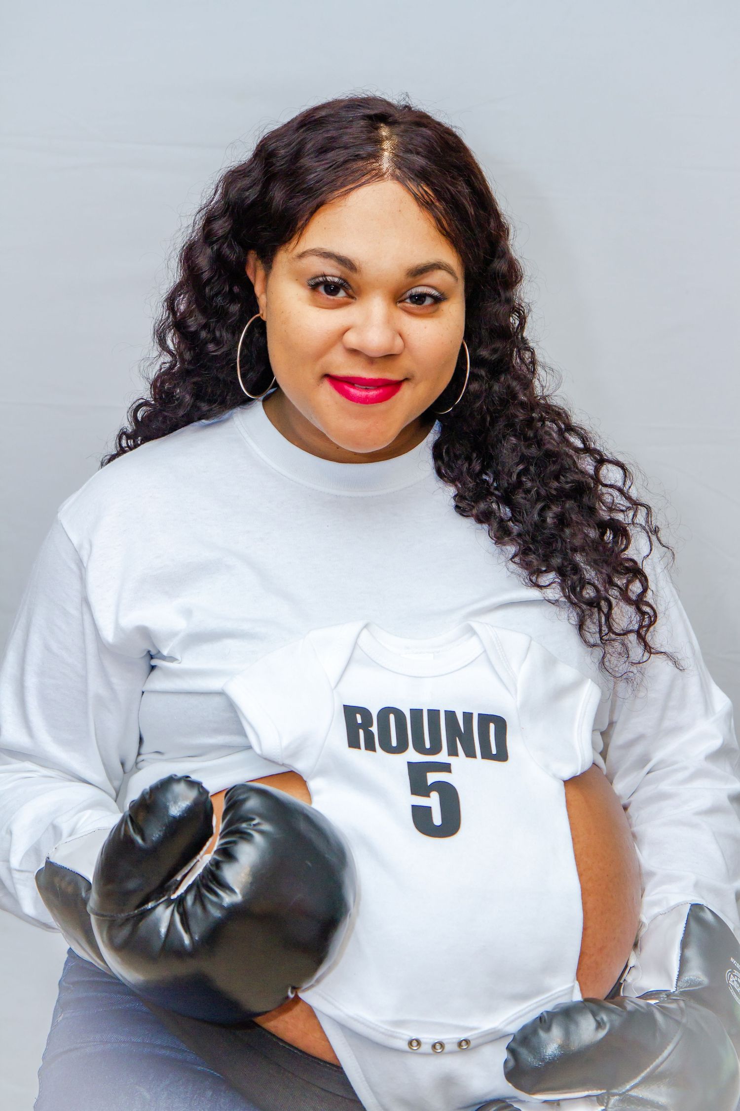 Boxer poses in white Round 5 shirt with black boxing gloves.