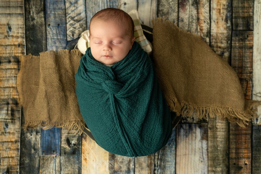 Sleeping newborn baby boy in a green wrap