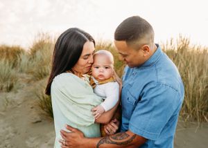 Family sharing intimate moment together on beach during sunset.