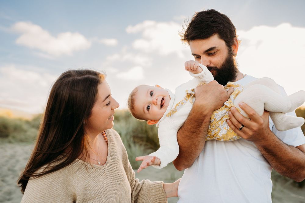 A family sharing playful moments together outdoors against a cloudy sky.