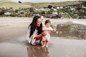 Mother and child playing together at the beach during a sunny day.