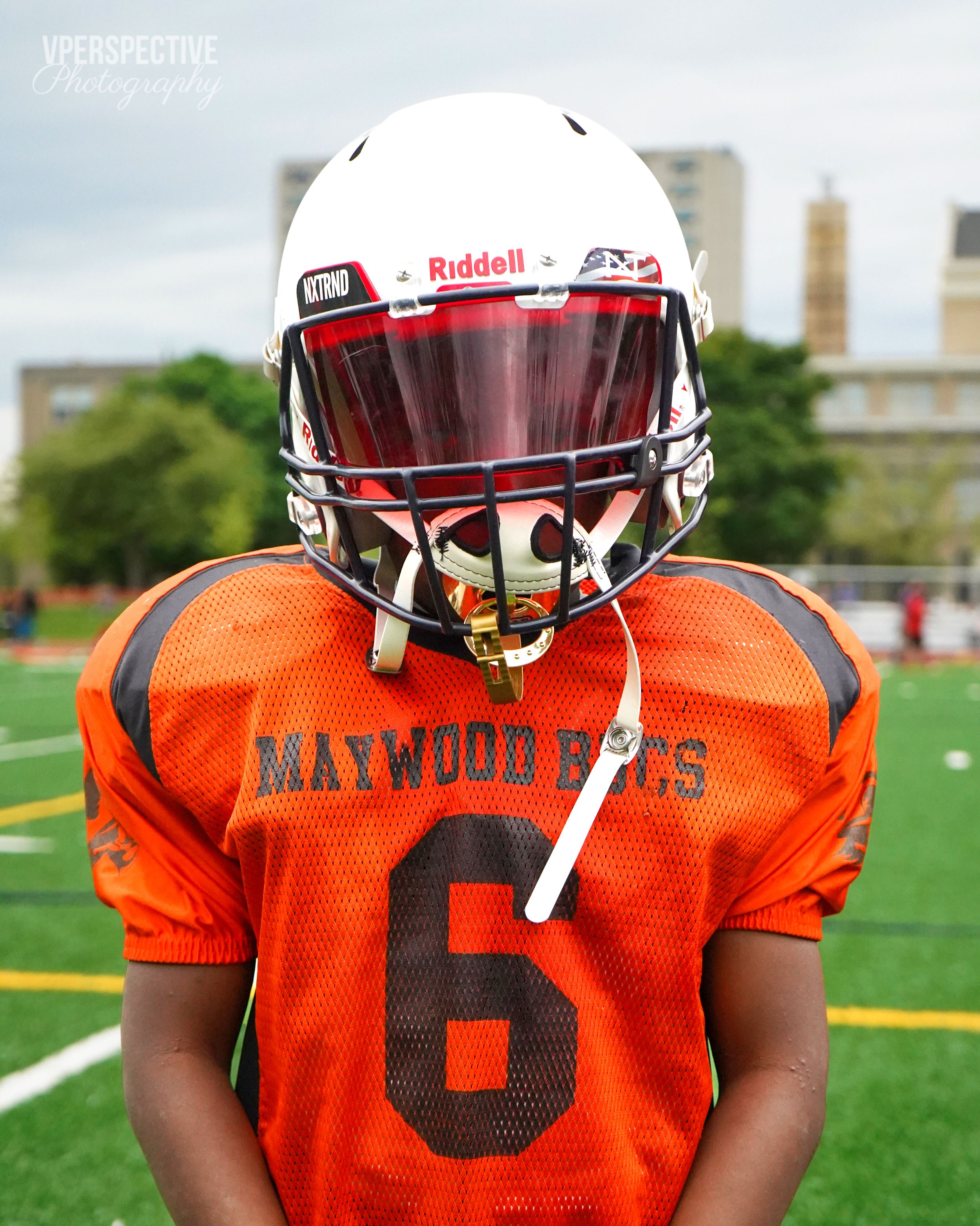 Maywood Jets player wearing orange jersey number 6 and white helmet on football field.