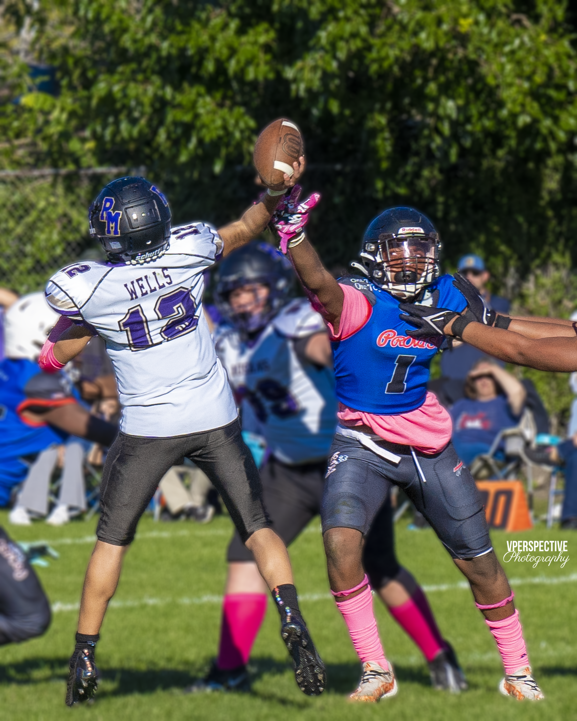 Two football players jump for the ball during competitive game action.