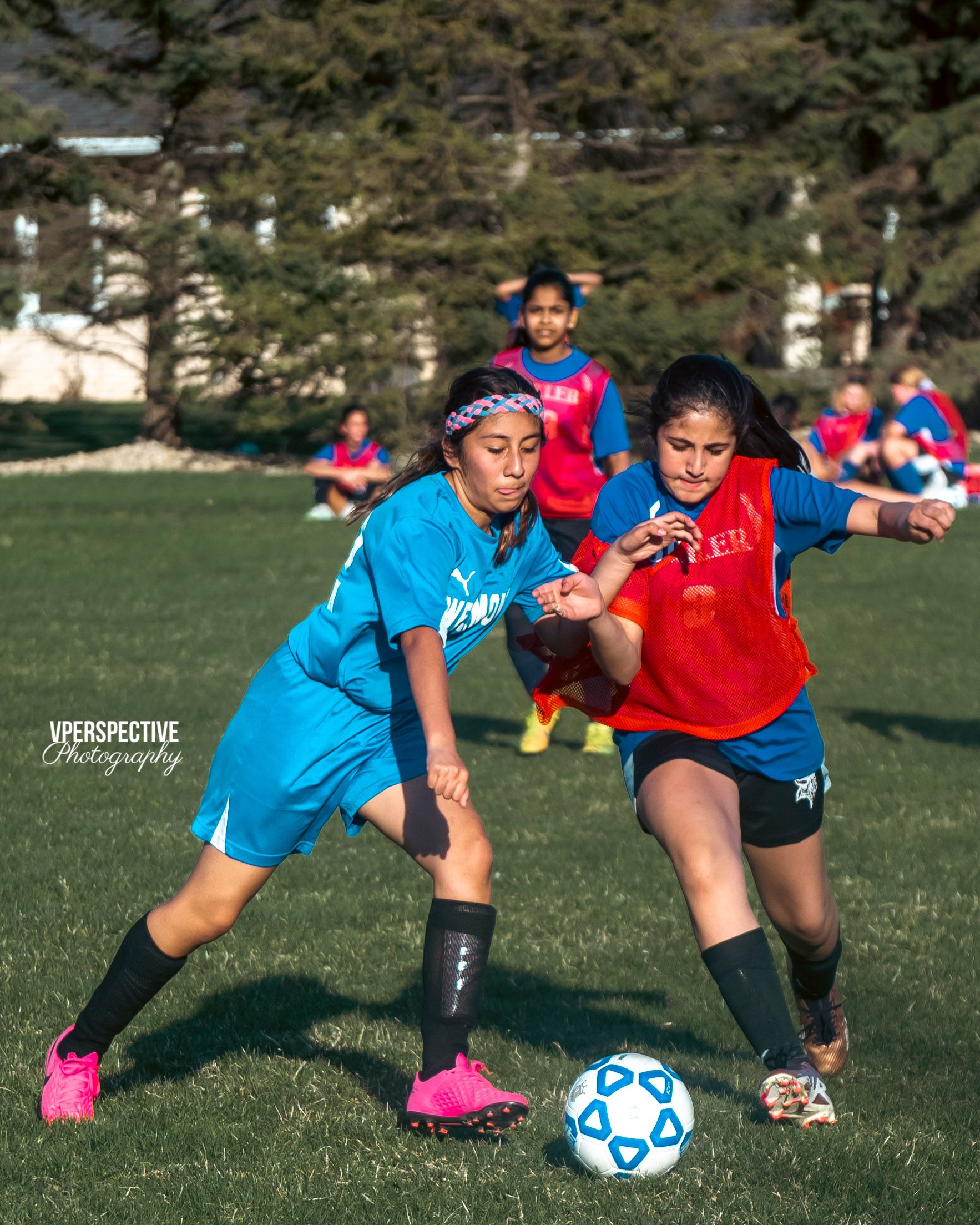 Two youth soccer players battle for possession of the ball during a match.