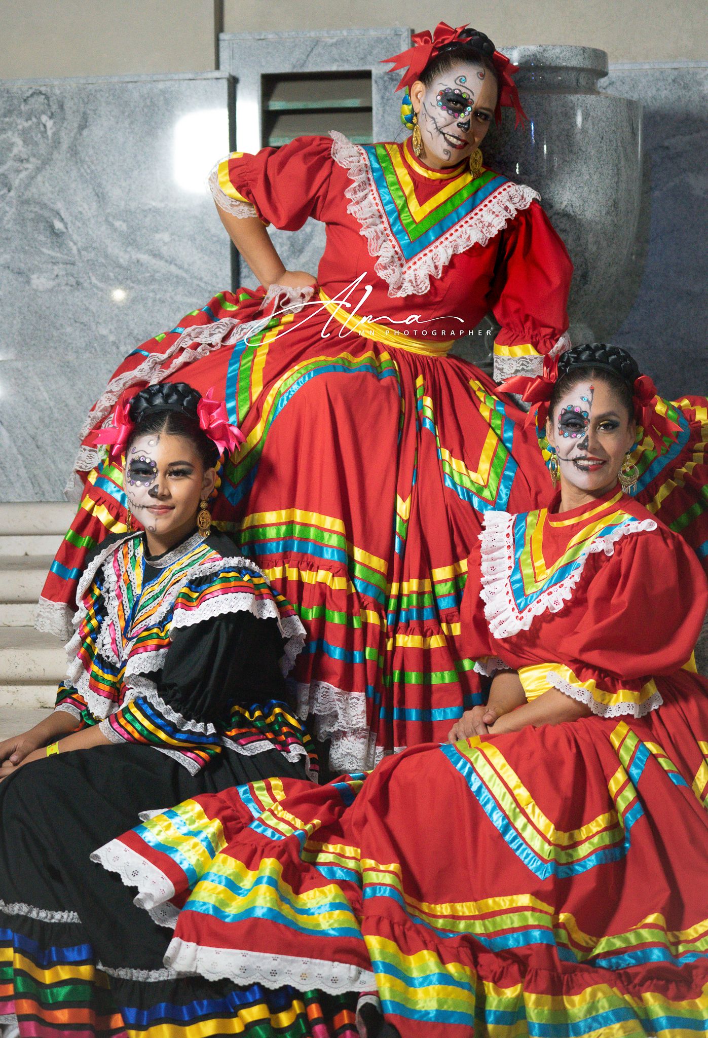 Traditional Mexican dancers in vibrant red dresses with colorful ruffles perform in traditional Dia de los Muertos attire.