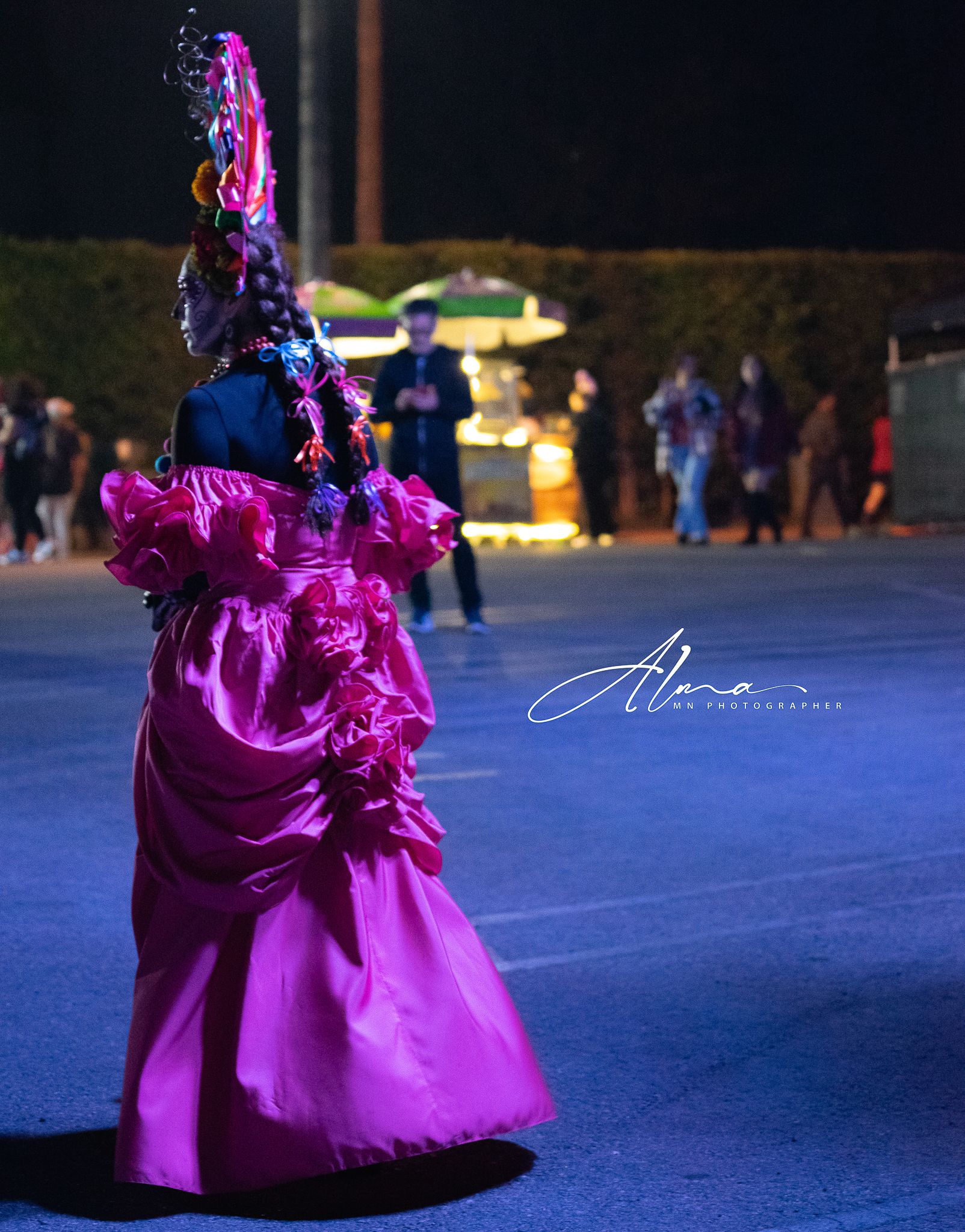 Dancer in bright magenta dress performs under nighttime lighting.