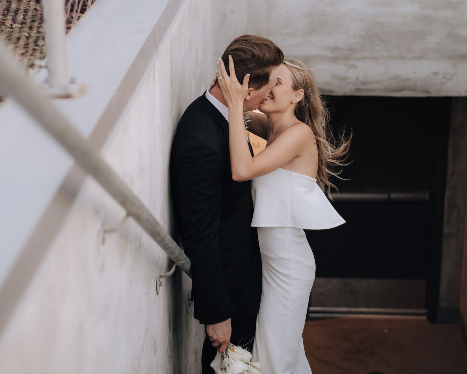 Elegant couple embraces on stairwell during intimate wedding photoshoot.