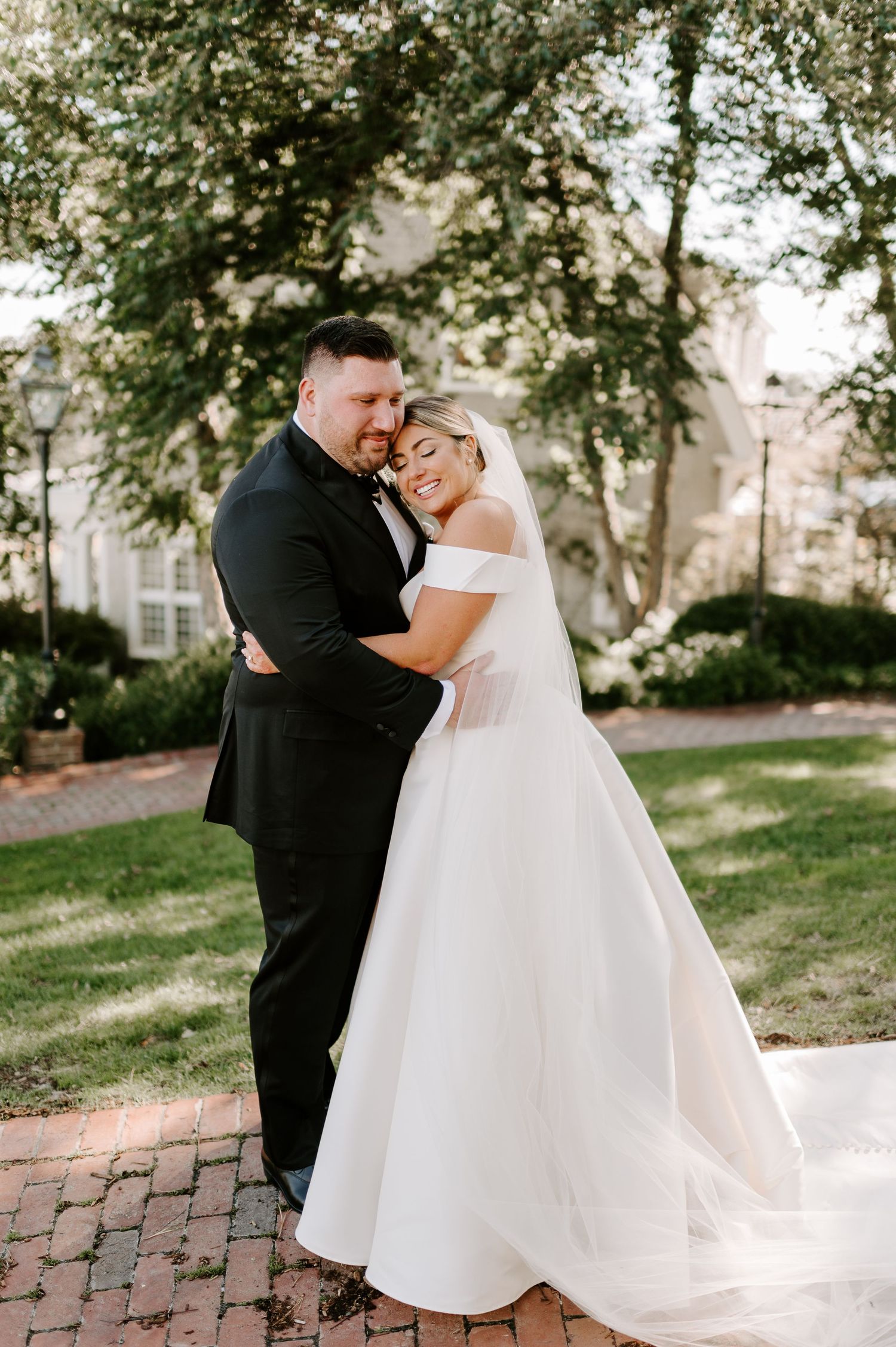 Couple shares intimate moment in elegant wedding attire outdoors.