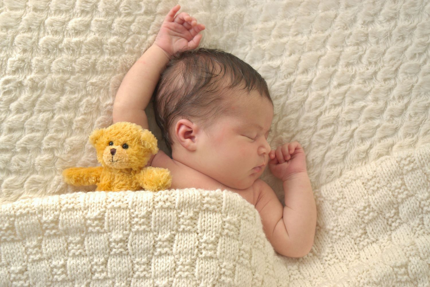 Newborn baby tucked up in bed with Teddy bear. Newborn Photography session ashford kent