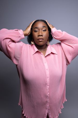 Fashion portrait in pink ribbed button-down shirt against gray studio background.