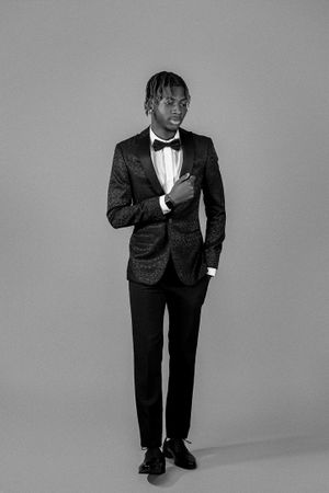 Stylish black and white portrait of person in textured tuxedo jacket and bowtie.