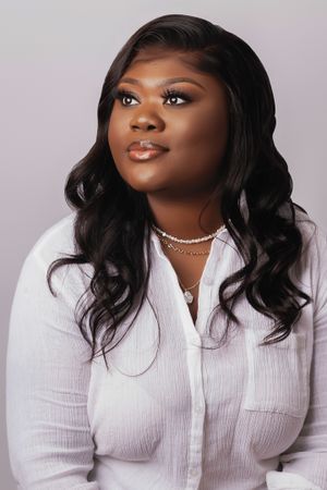 Professional headshot with soft lighting featuring white button-down shirt and wavy hair.
