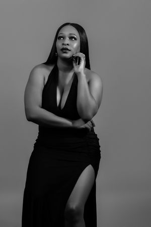 Dramatic black and white portrait featuring elegant black evening gown with thigh-high slit.