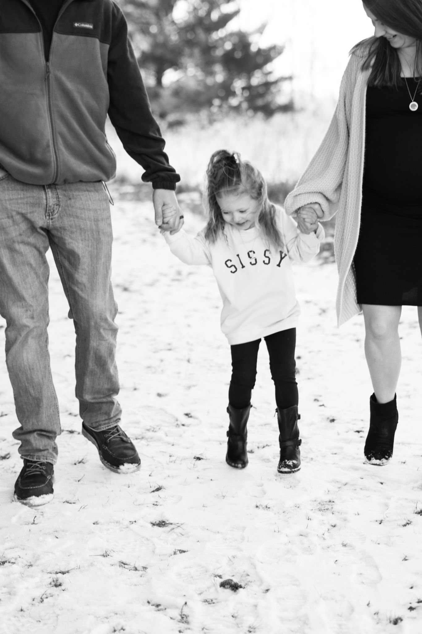 Family walking together in snow while holding hands with child in the middle.