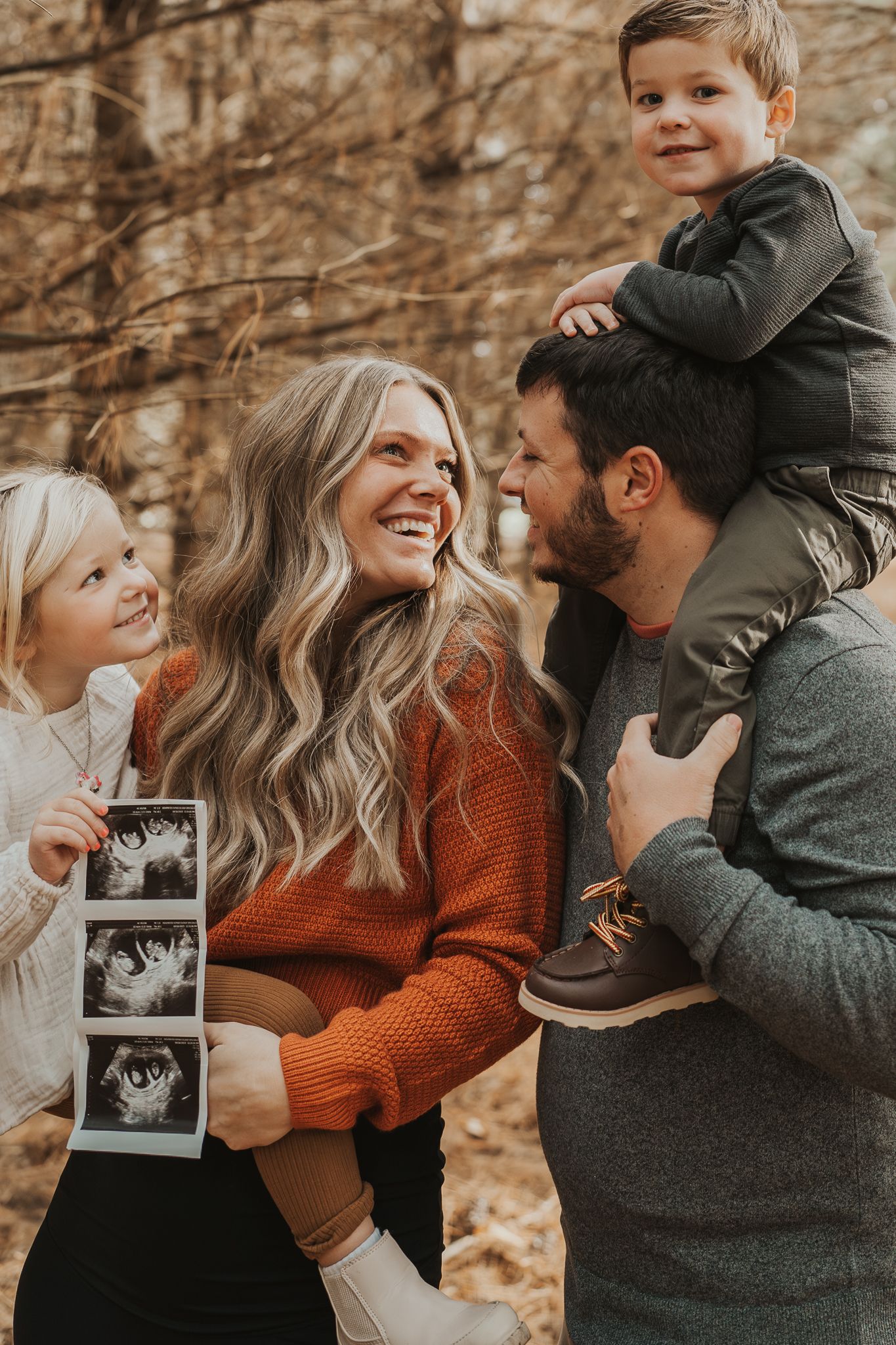 Michigan maternity photograph of family holding ultrasound photo during fall woodland photoshoot in southern Michigan.