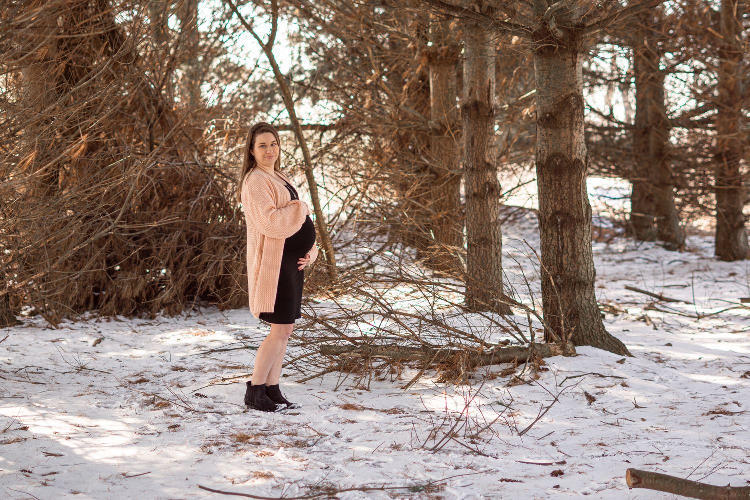 Person in pink dress standing in snowy winter forest setting.
