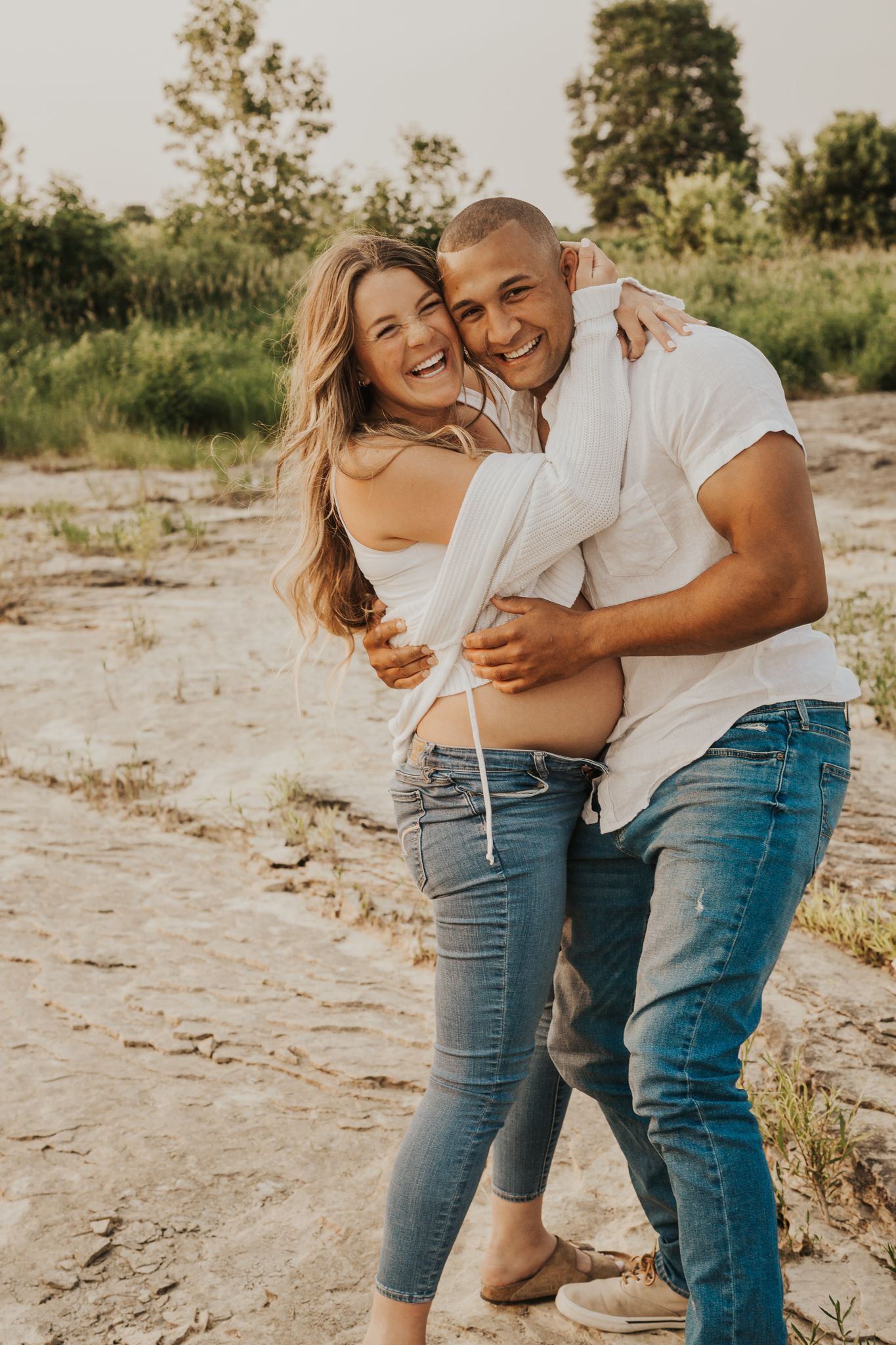 Couple laughs together in matching denim during casual outdoor photo session.