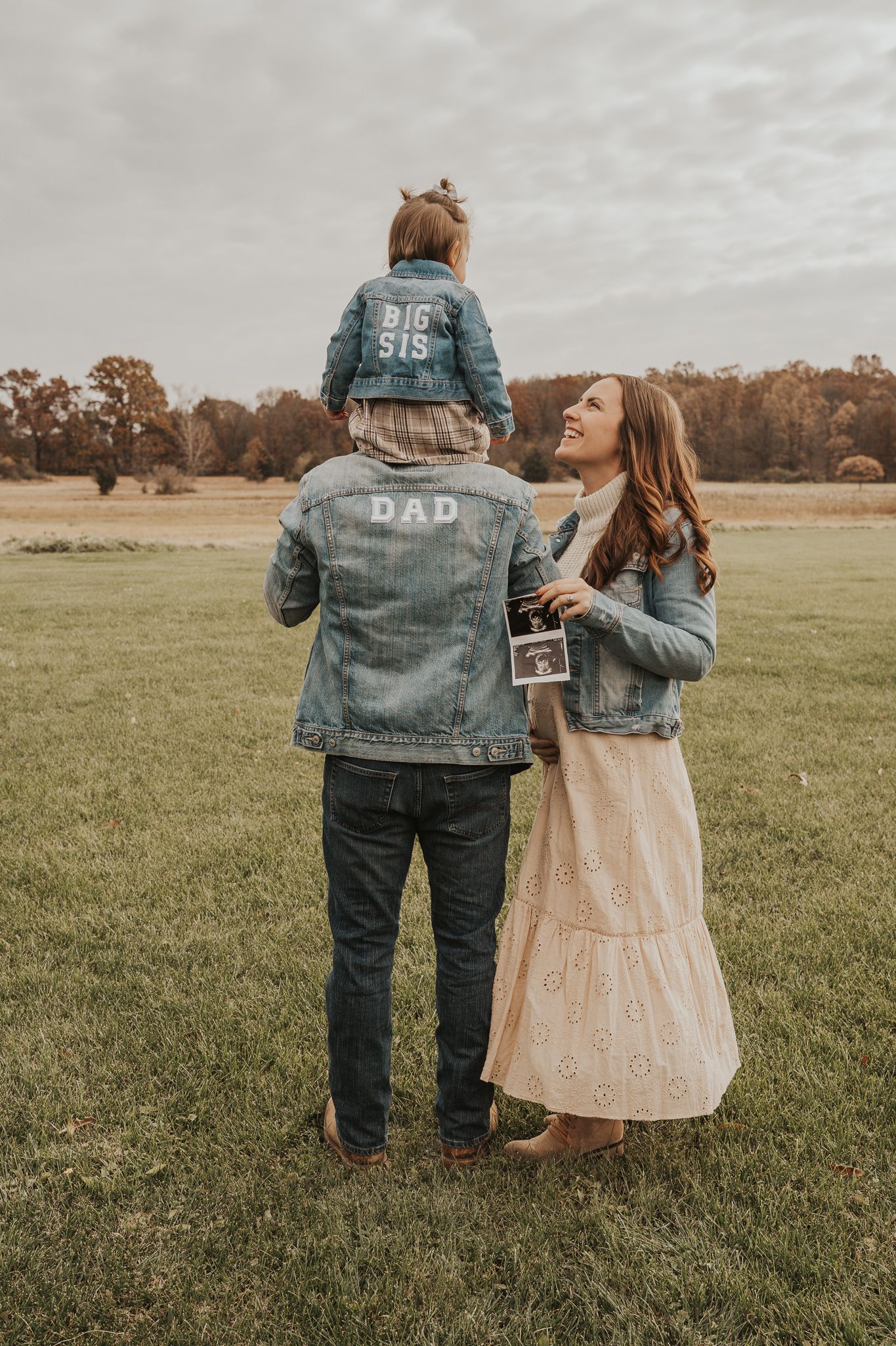 Sweet family photos showing custom denim jackets in a golden field at sunset.