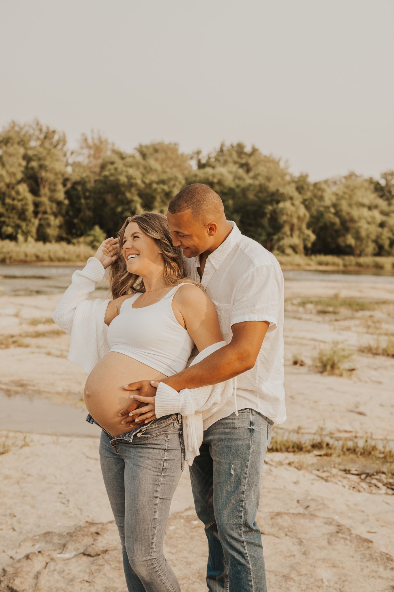 Intimate maternity photo session on sandy beach at sunset.