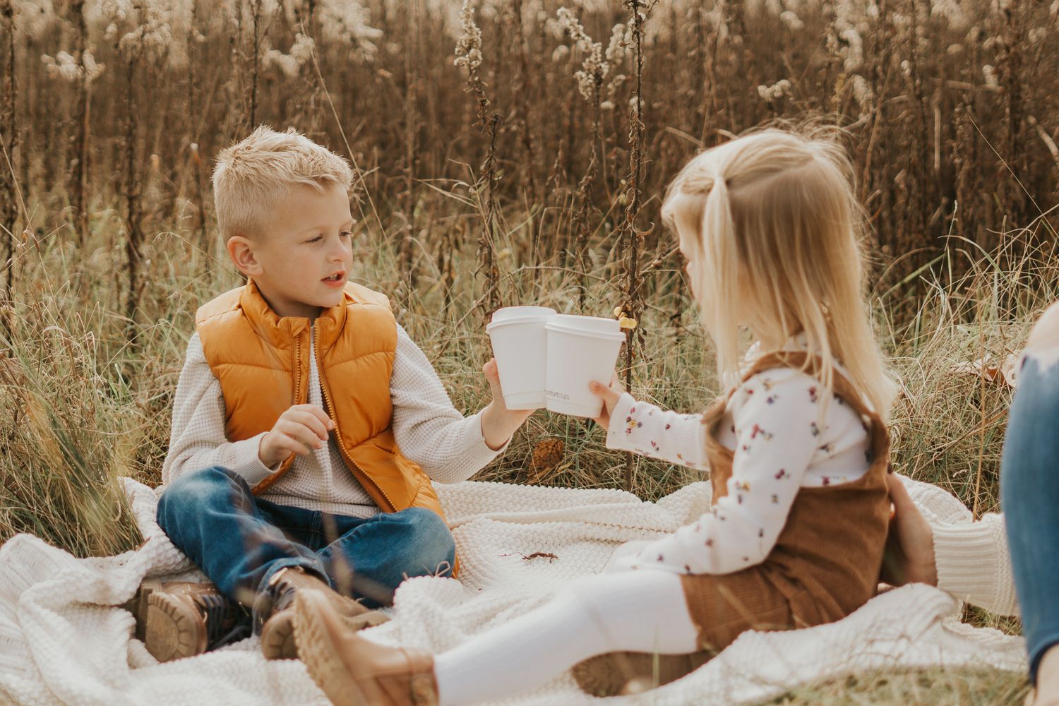 Family members sitting together in tall autumn grass during an outdoor photo session.