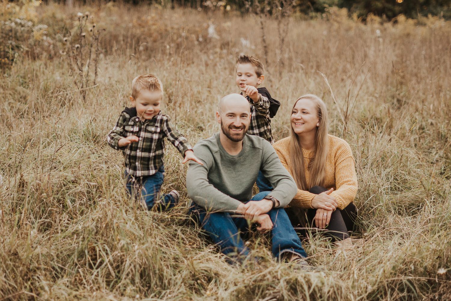 Candid family moments captured while sitting together in a golden autumn field.