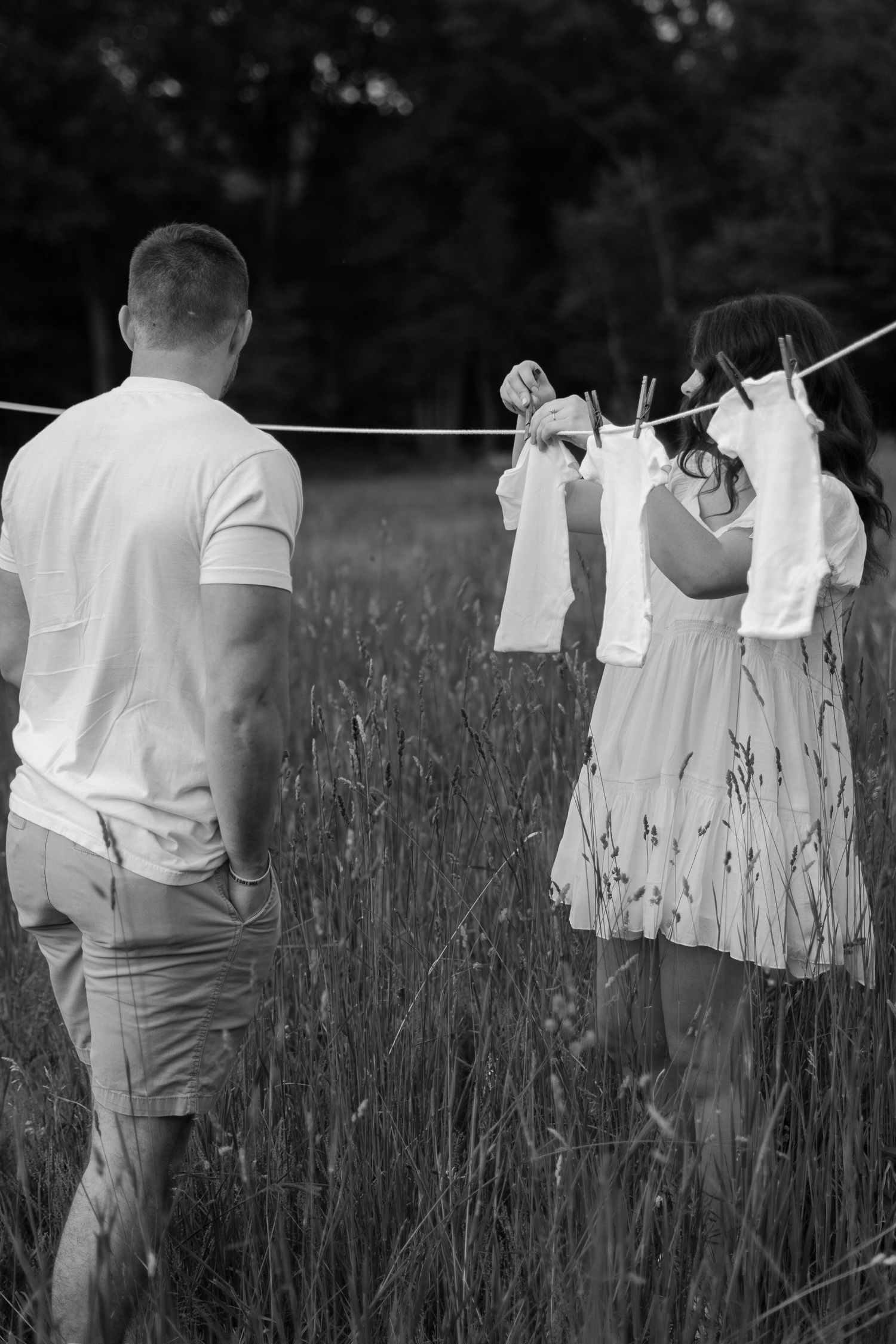 White clothing hanging on a clothesline in a field of tall grass at dusk.