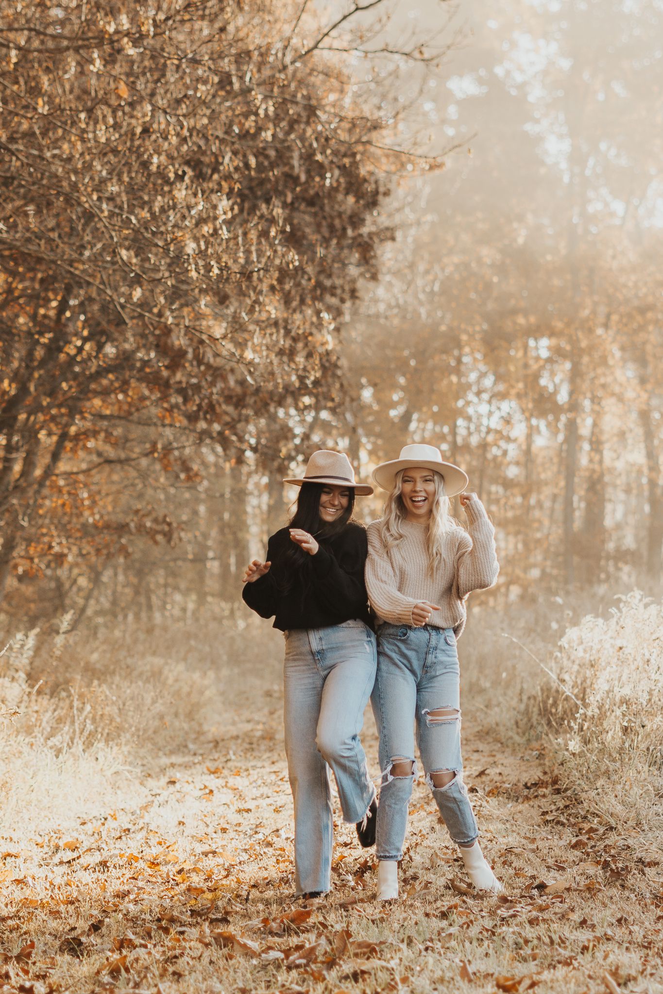 Best friends in casual denim and sweaters enjoying a playful moment in a Jackson MI woodland setting.