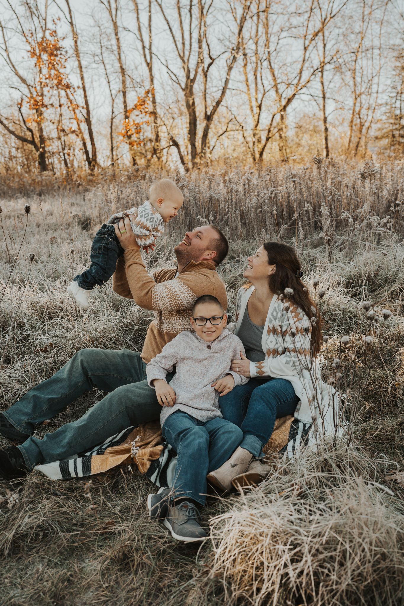 Family lying in autumn grass having fun and laughing together during outdoor photo session.