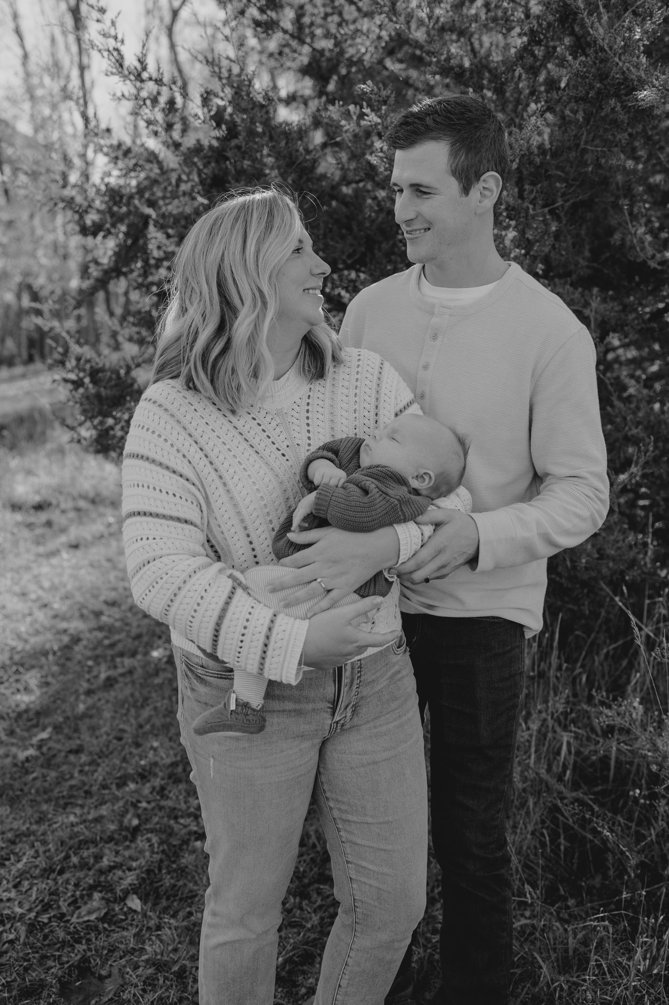 A series of candid moments between a couple and child in matching light-colored outfits against natural foliage in Pulaski Michigan.