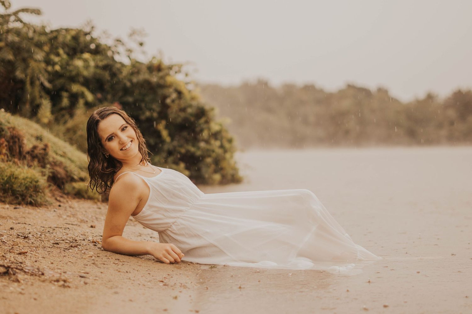 A flowing white fabric dances in the breeze along a scenic shoreline.
