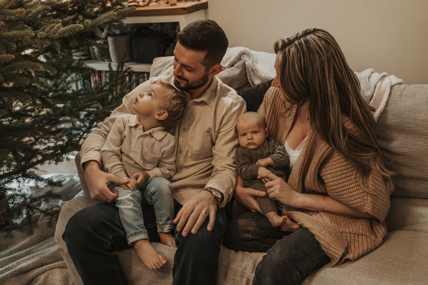 Indoor family lifestyle scene with Christmas tree and warm neutral decor taken in home by Ann Arbor MI.