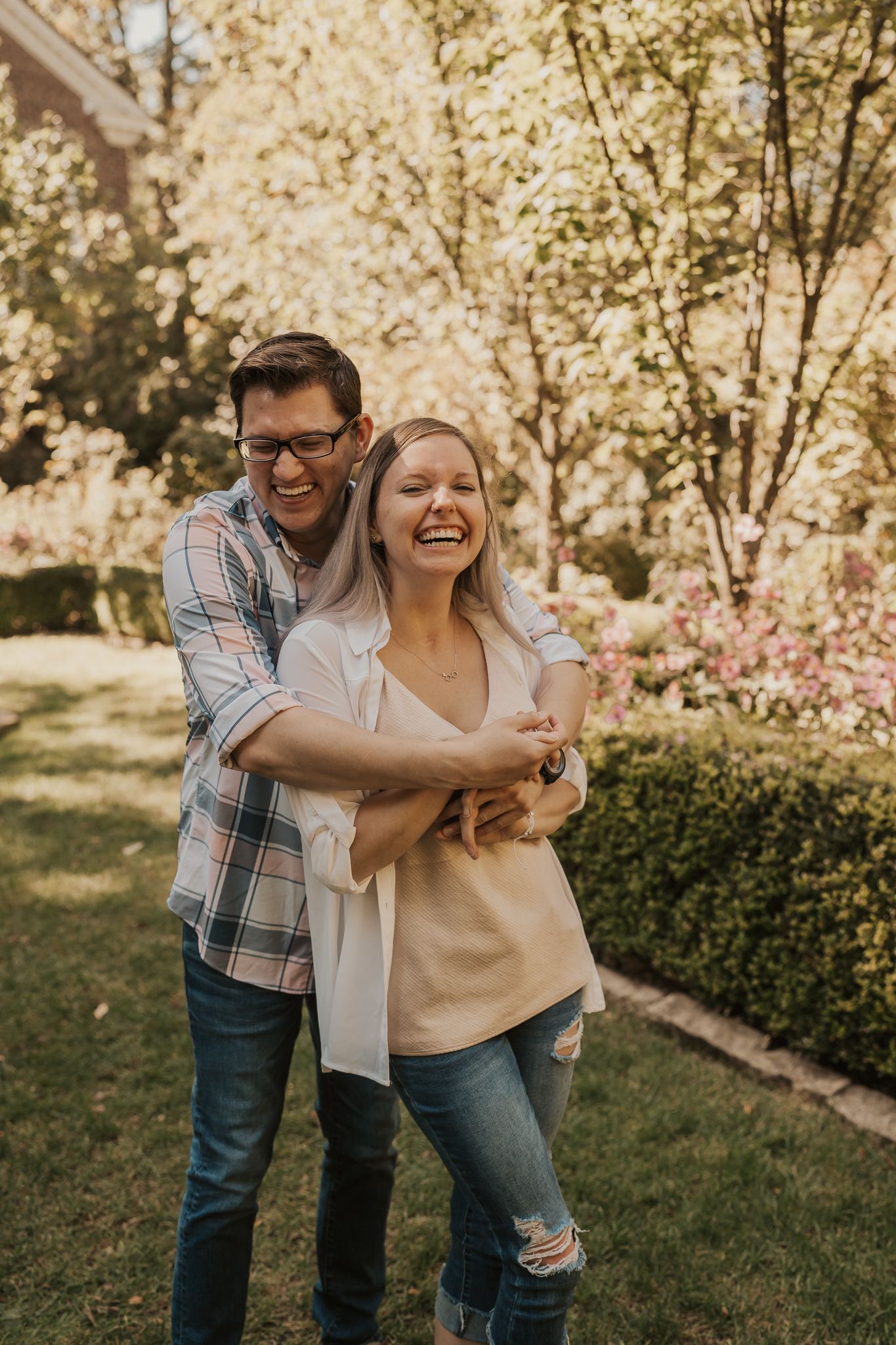 Couple sharing laughs while dancing under blooming spring trees.