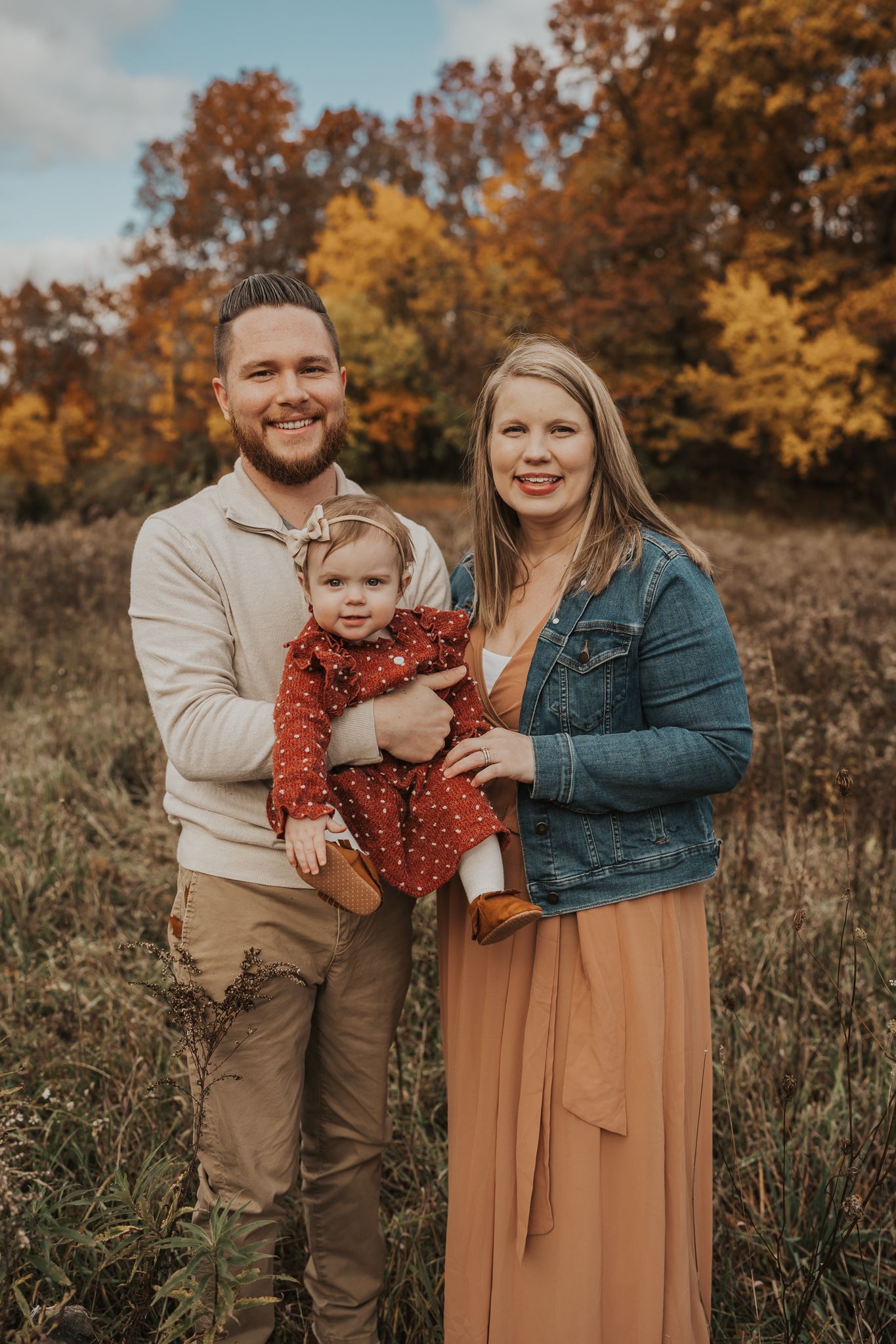 Outdoor family portrait session during fall with autumn colors in background.
