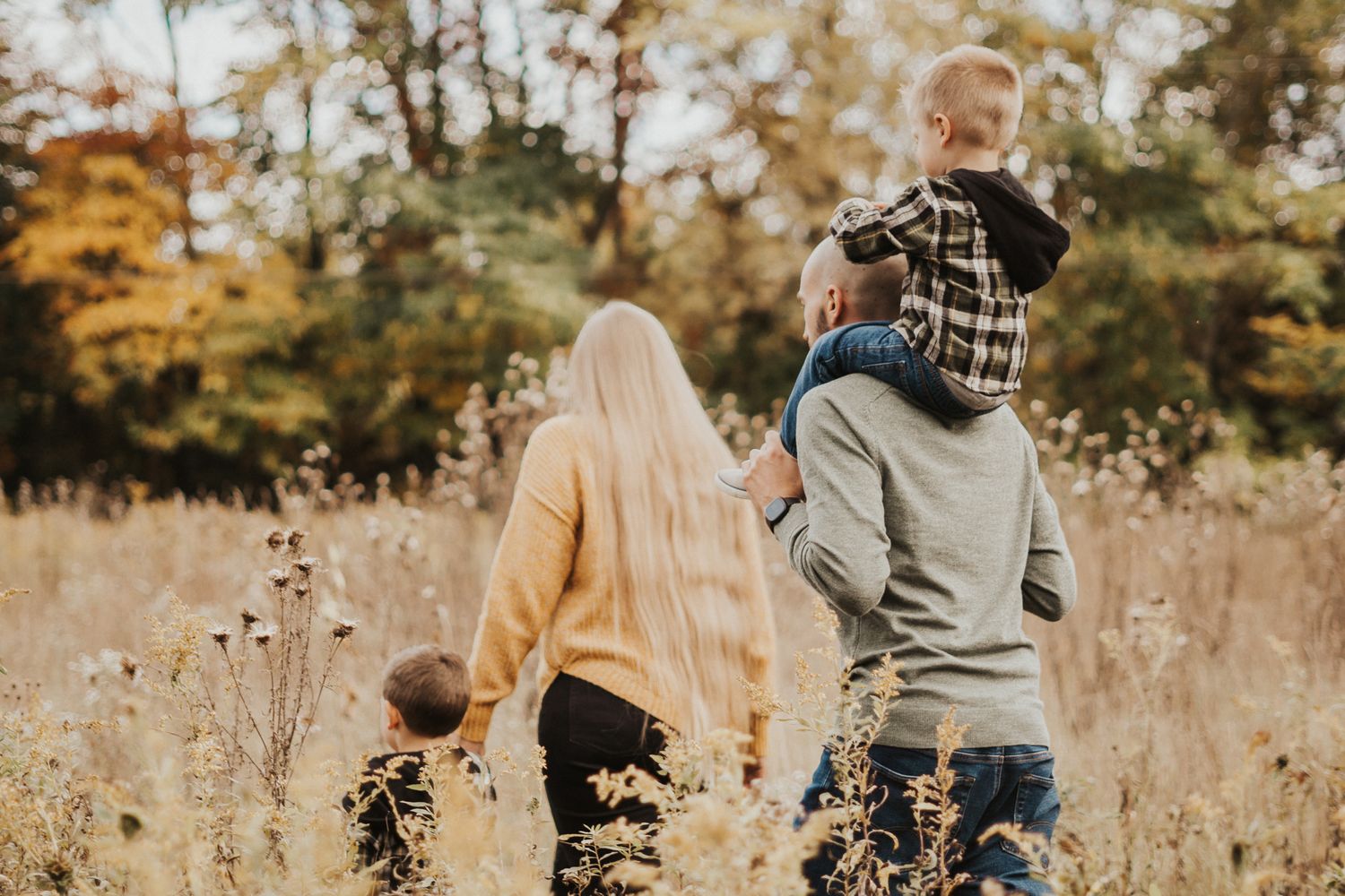 Family portrait session in a rustic field with autumn colors and natural lighting.