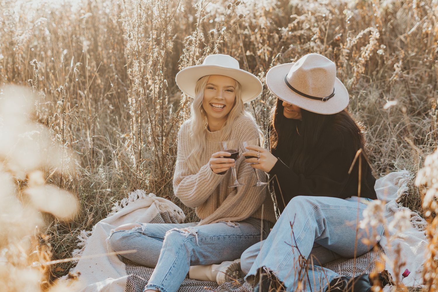 Friend photography session in Michigan, enjoying a sunny outdoor picnic with wine glasses and casual conversation.