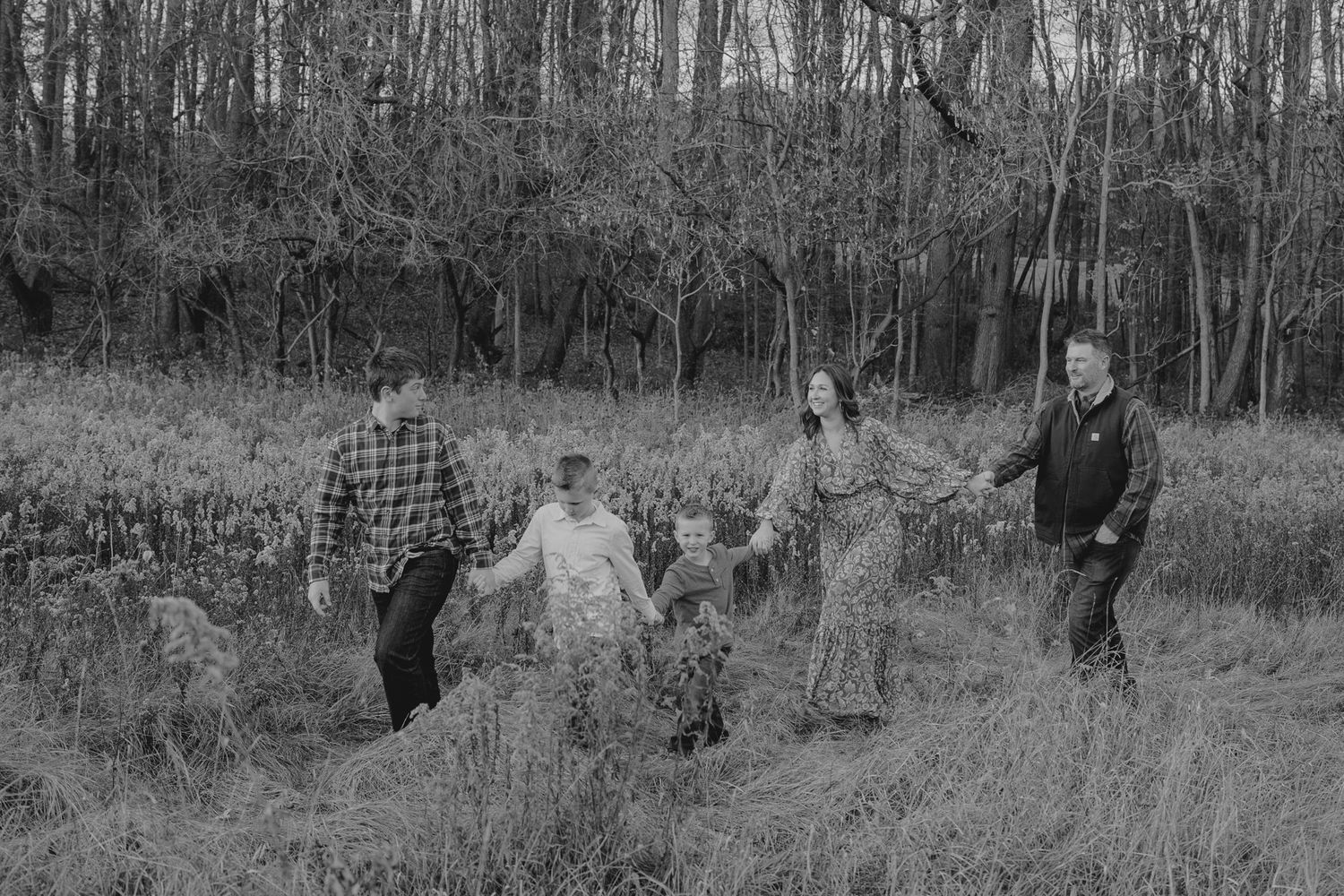 A Michigan family walks through a wooded area in black and white family photography.