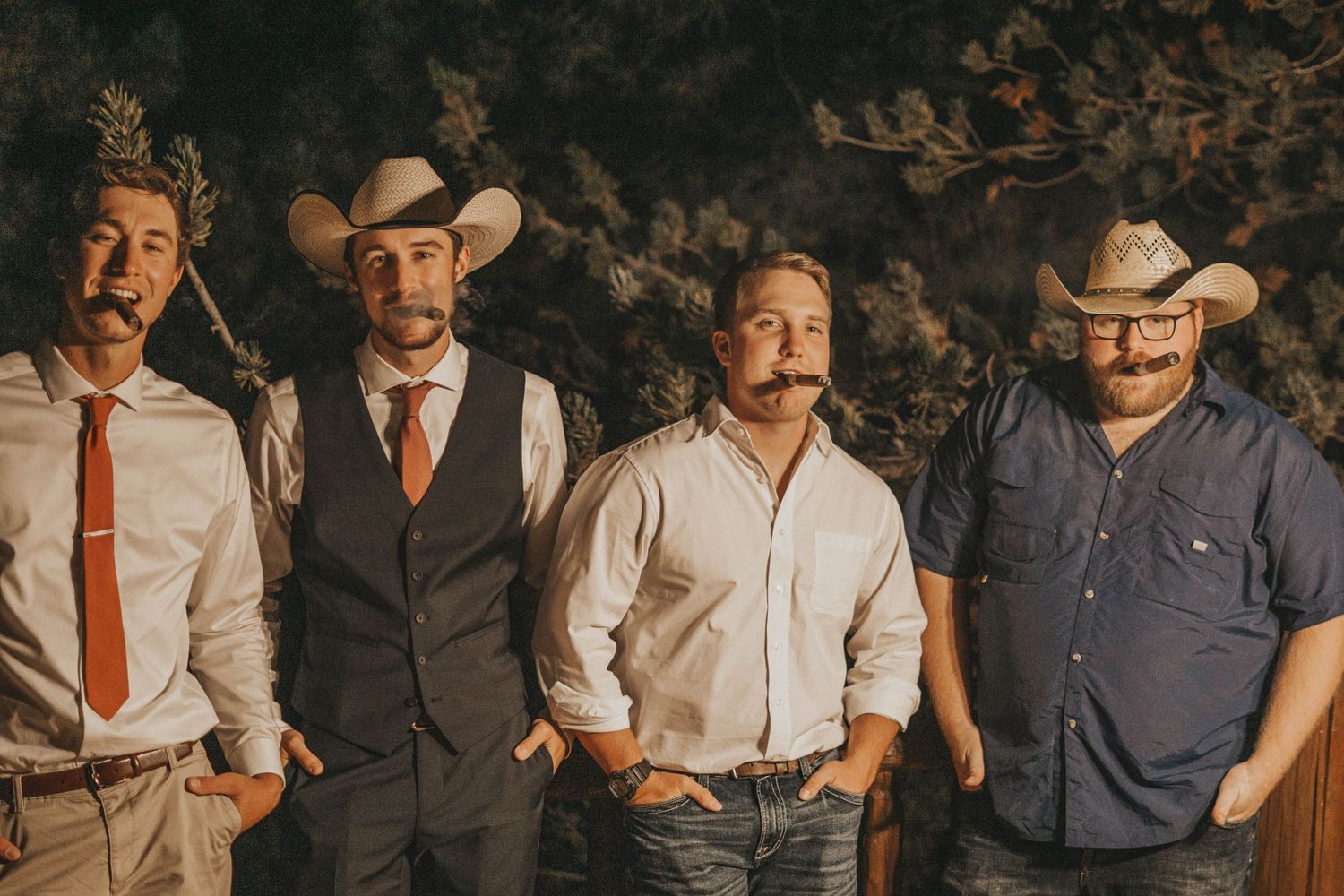 Bridal party wearing western attire poses together in Colorado sunset for a casual portrait.