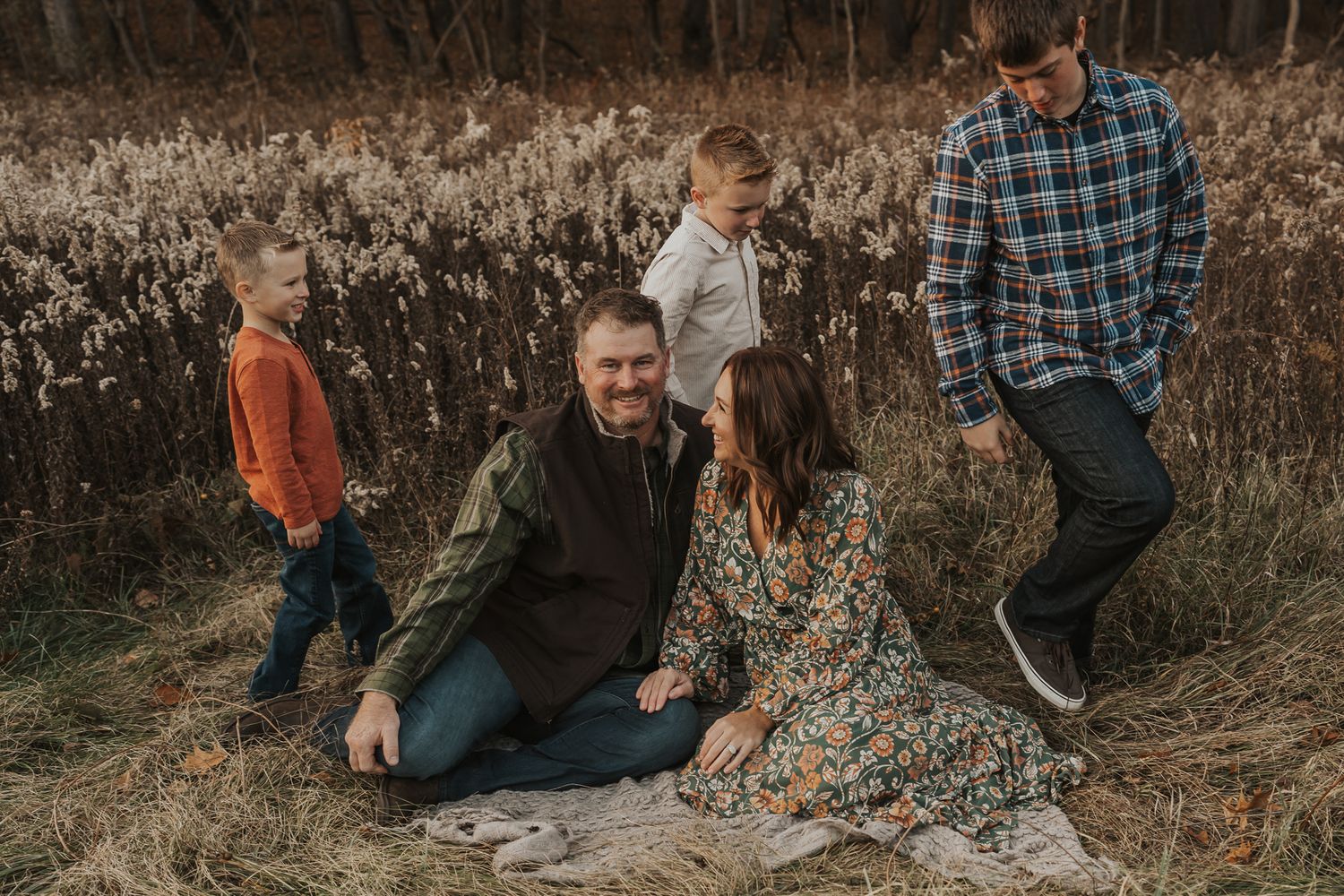 Candid family moments captured in a field with natural fall scenery.