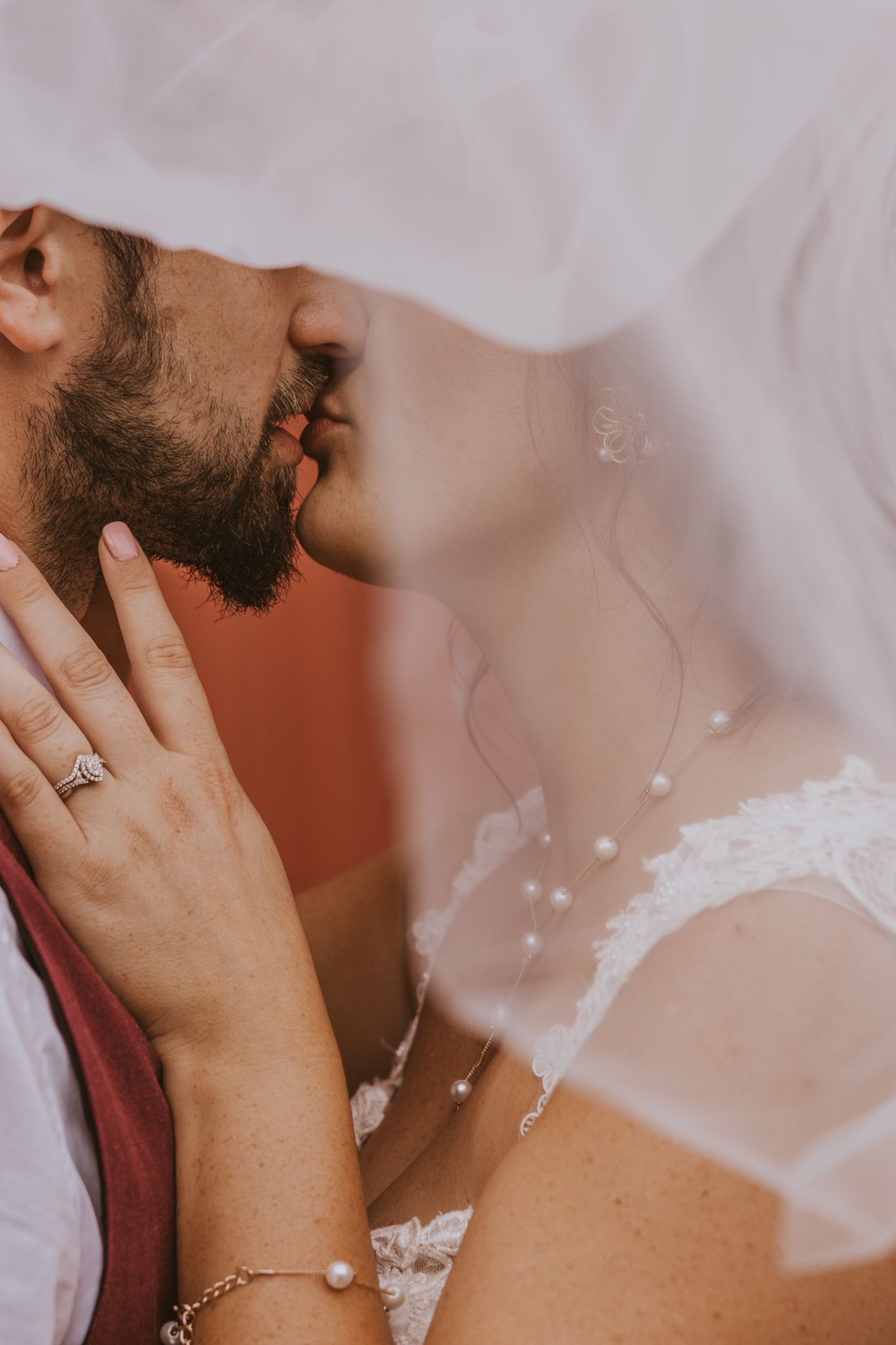 Close-up details of tender moments and wedding attire with a white veil in focus.
