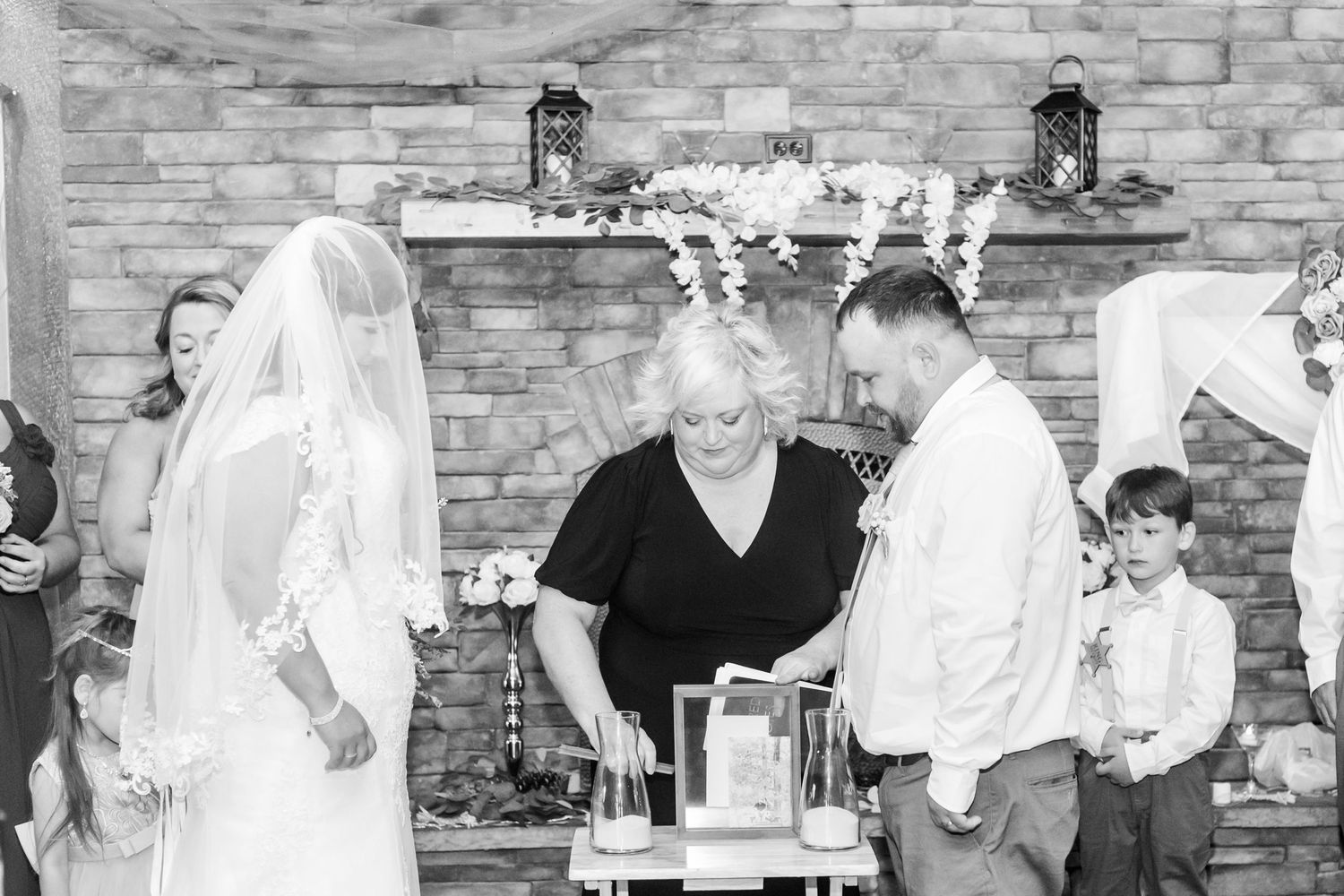 Wedding party posing against a rustic stone wall in black and white photography.