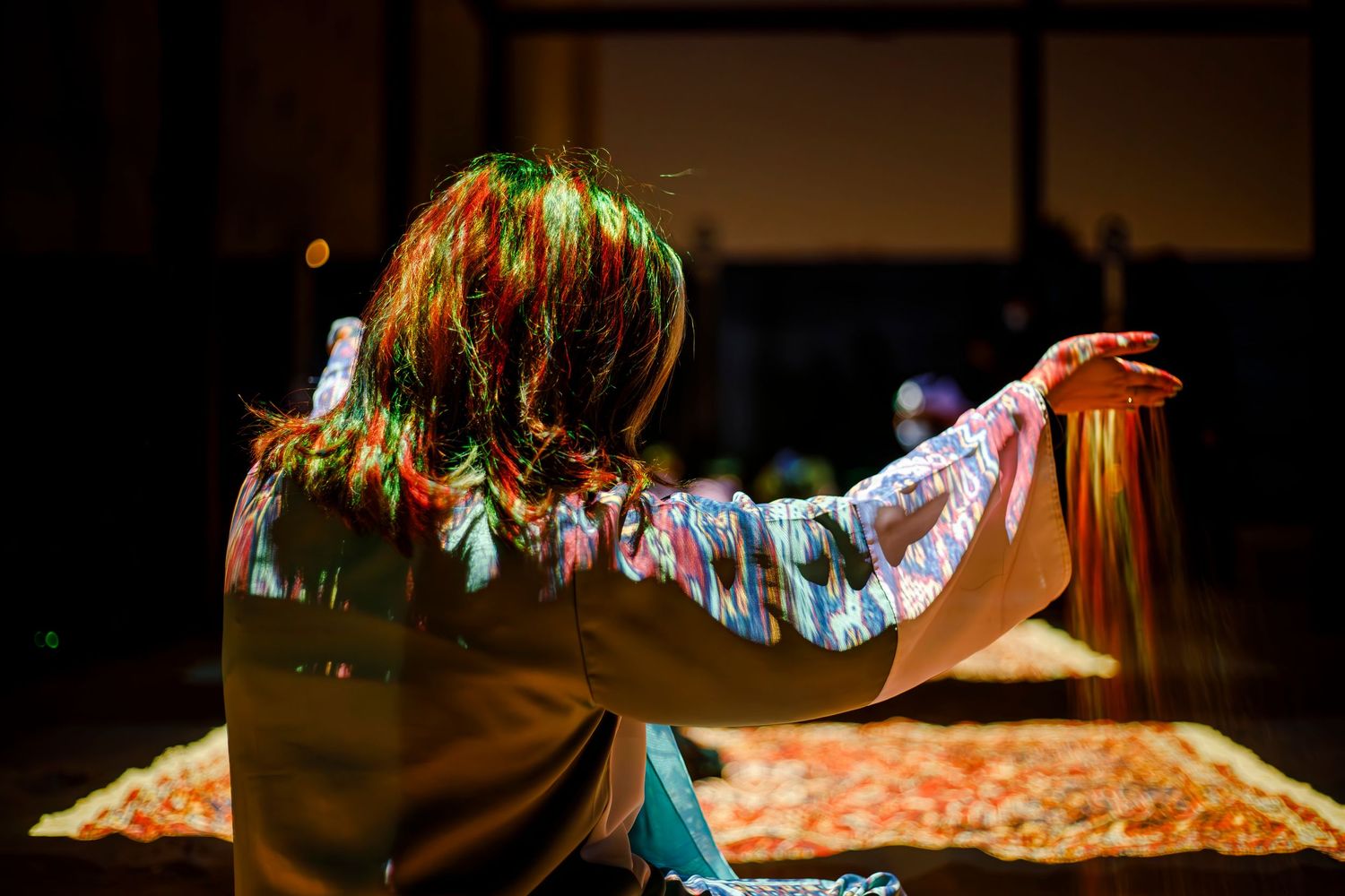 Colorful stage lighting illuminates a performer making expressive gestures.