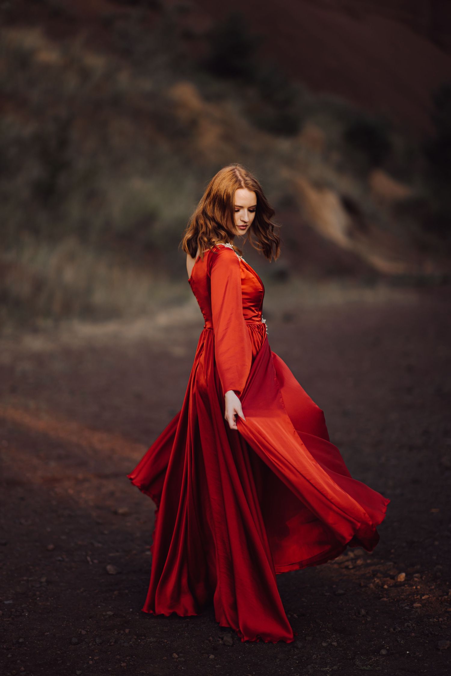 Flowing red dress catches movement in dramatic mountain landscape.